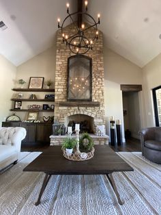 a living room with a large stone fireplace and chandelier hanging from the ceiling