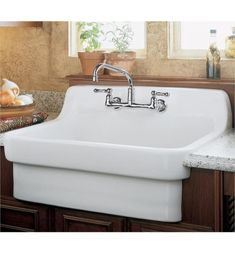 a large white sink sitting on top of a counter next to a wooden cabinet and window