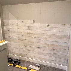 the wall is being painted white with wood planks and tools on the floor next to it