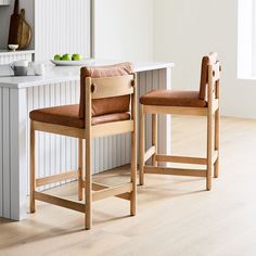 two wooden chairs sitting next to each other on top of a hard wood floored kitchen