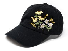 a black hat with embroidered daisies on the front and back side, against a white background