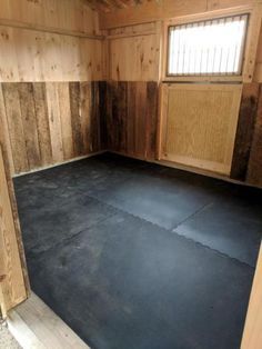 an empty room with wooden walls and black floor