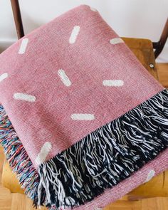 a pink and black blanket sitting on top of a wooden chair