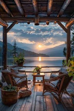 a wooden deck with chairs and tables on it near the water at sunset or dawn