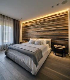 a bed room with a neatly made bed next to a window and a wooden wall