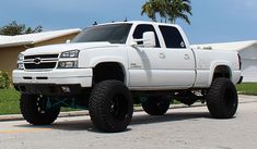 a white truck parked in front of a house with palm trees on the other side