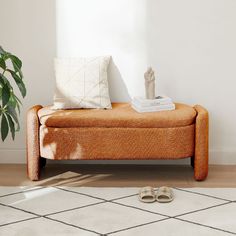 a living room with an orange couch and white rug on the floor next to a potted plant