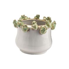 a white vase with green flowers on the rim and gold trimmings, set against a white background