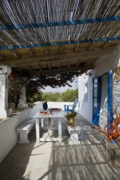 an outdoor dining area with white walls and blue trim on the roof, along with potted plants