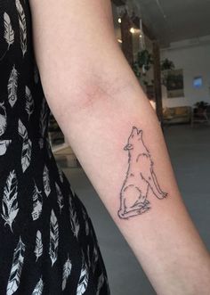 a woman's arm with a small tattoo of a dog