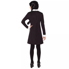 the back view of a woman in a black coat and white collared shirt, with her hands on her hips