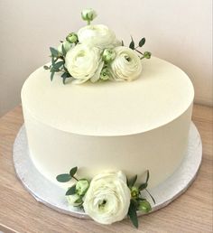 there is a white cake with flowers on the top and bottom, sitting on a table