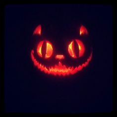 a lit up pumpkin with glowing eyes in the dark, looking like a cat's face