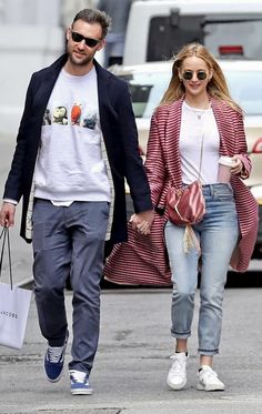 a man and woman are walking down the street holding hands with each other while carrying shopping bags