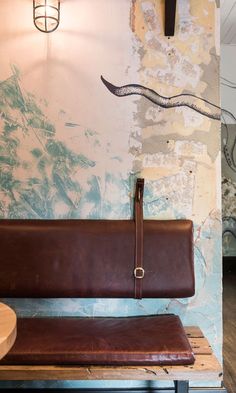 a brown leather bench in front of a wall with a snake painted on the wall