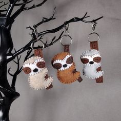 three little stuffed animals hanging from hooks on a tree