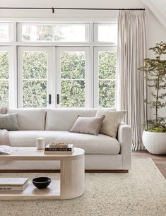 a living room with white couches and large windows in it's center area