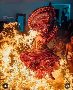 a woman dressed in red is dancing around some fire with her headdress on