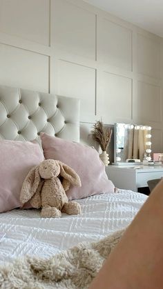 a stuffed animal sitting on top of a bed next to pillows in a room with white walls