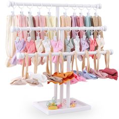 an assortment of baby clothes hanging on a white rack with hooks and clips to hang them