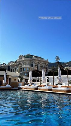 an outdoor swimming pool with lounge chairs and umbrellas in front of a large building