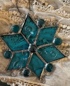 a glass and metal snowflake sitting on top of a lace covered table cloth