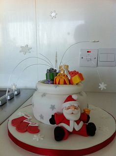 a santa clause sitting on top of a white counter next to christmas decorations and gifts