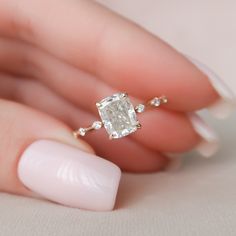 a woman's hand holding an engagement ring with a large diamond in the middle