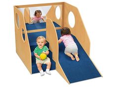 two toddlers playing in a wooden play house with blue carpet and walls, while another child plays on the other side