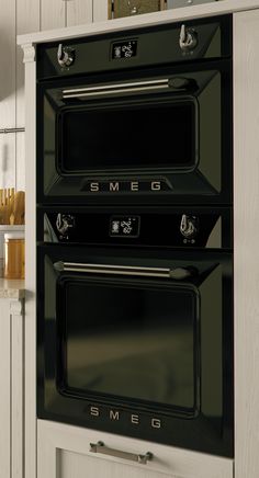 two black ovens sitting side by side in a kitchen with white cabinets and counter tops