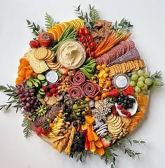 a circular platter filled with different types of cheeses, crackers and fruit