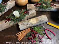 some candles are sitting on wooden logs with berries and pine cones around them, surrounded by other items