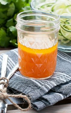 a glass jar filled with liquid sitting on top of a table next to some vegetables