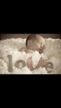 a baby is laying down in a blanket with the word love spelled out next to it