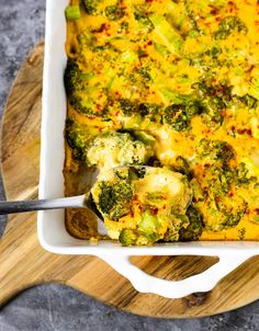 a casserole dish with broccoli and cheese in it on a cutting board