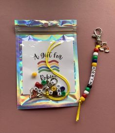 a key chain with some beads on it next to a card that says a gift for baby