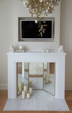 a white fireplace with candles on the mantle and a chandelier hanging above it