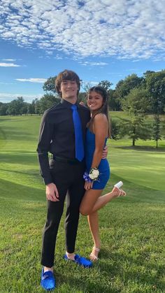 a man and woman in formal wear posing for a photo on the golf course with blue shoes