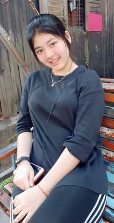 a young woman sitting on top of a wooden bench