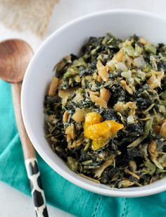 a white bowl filled with spinach and oranges on top of a blue towel