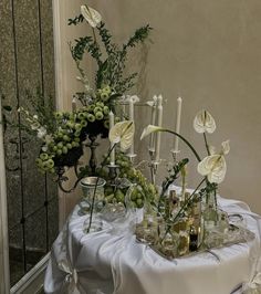 an arrangement of flowers and candles on a table