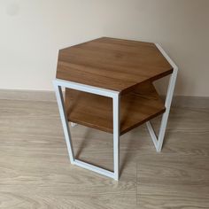 a wooden table with white legs and a shelf on the top that is shaped like an octagon