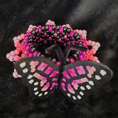 Pink/Black colored Butterfly Kandi Cuff! This Kandi cuff is handmade by me.  Perfect for accessorizing your festival outfits or any rave outfit, or to add to any awesome Kandi collection!! Check out/follow my socials (@ TicTacToeCreations on FB and IG + linktr.ee/TicTacToeCreations ) for more fun things that haven't been posted on shops yet.  I happily do custom orders of many of the things posted on my socials as well!  💖⭐ Thanks!  🫶PLUR⭐💖 Funky Handmade Black Jewelry, Handmade Bracelets For Party And Festival, Handmade Rave Jewelry For Party, Handmade Pink Rave Bracelets, Handmade Adjustable Rave Jewelry, Pink Beaded Rave Jewelry, Handmade Funky Jewelry For Festivals, Funky Handmade Jewelry For Festivals, Funky Handmade Festival Jewelry