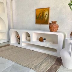 a living room with white furniture and potted plants on the shelf next to it