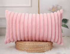 a pink pillow sitting on top of a wicker basket