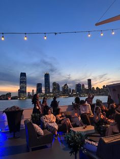 a group of people sitting on couches in front of a city skyline at night