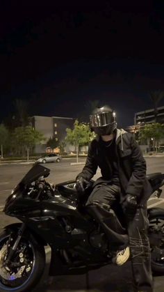 a man sitting on top of a black motorcycle in the middle of a parking lot