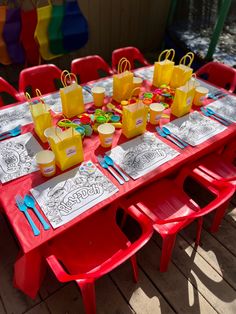 a red table topped with lots of yellow bags and plastic chairs next to each other