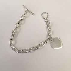 "Oval shaped large link chain in sterling silver with one heart charm.  Heart charm measures 24 mm tall and 0 mm wide.  The links measure 12 mm long by 7 mm wide and are solid.  The bracelet has a toggle clasp. The length of the bracelet is 7 1/2\".  This was preowned.  It is in good condition." Classic Sterling Silver Charm Bracelet With Heart, Classic Sterling Silver Heart Charm Bracelet, Classic Silver Heart Bracelet, Classic Silver Chain Charm Bracelet With Oval Links, Classic Silver Heart Charm Bracelet, Classic Silver Heart Bracelet With Lobster Clasp, Sterling Silver Charm Bracelet With Toggle Clasp, Minimalist Silver Chain Bracelet With Heart Charm, Personalized Silver Oval Link Chain Bracelet