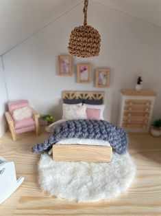 a doll house bedroom with a bed, chair and book on the floor in front of it